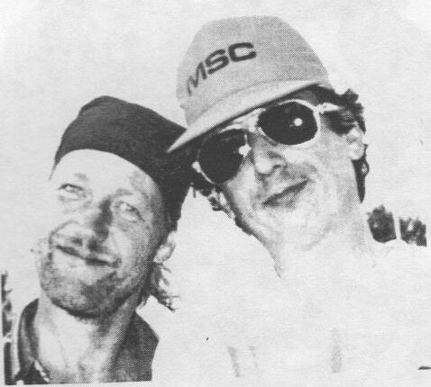 Race committee members John Gilchrist and Barry Farrell, cheek to cheek, one in a cap and sunglasses