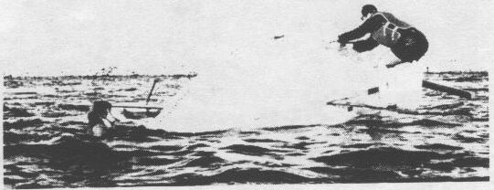 A sailor flying off a capsizing Albacore while another boat sails past in the chop