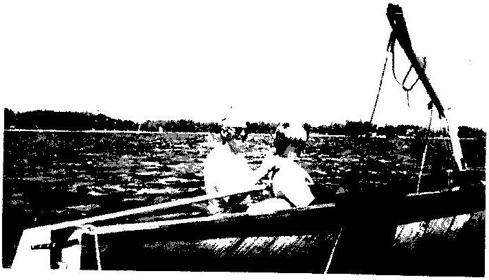 Two sailors in an Albacore on choppy water, the boom swung high