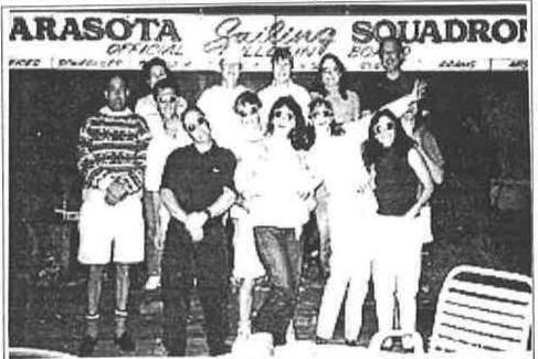 Group of Albacore sailors posing at night in front of the Sarasota Sailing Squadron official sailing board