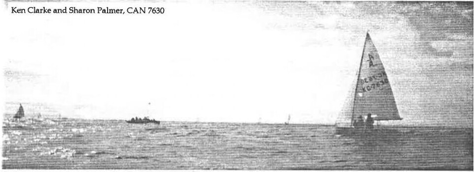 An Albacore sailing upwind on open water, a mark and a power boat in the distance