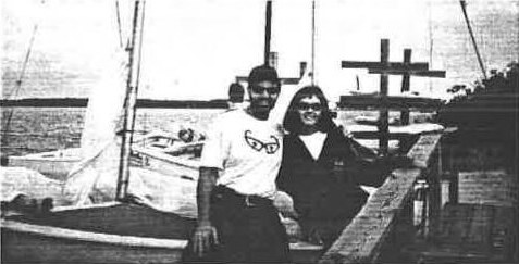 John Struthers and Heather Macnaughton smiling on a dock beside their rigged Albacore