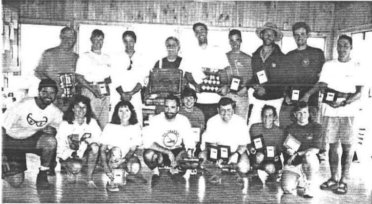 Group photo of about eighteen prize winners, a back row standing and a front row kneeling, holding trophies