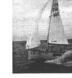 An Albacore dinghy, sail number USA 8011, sailing past a dock