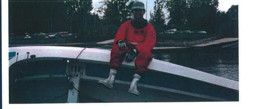 A sailor in a red drysuit sits on the gunwale of an Albacore during the annual buoyancy test