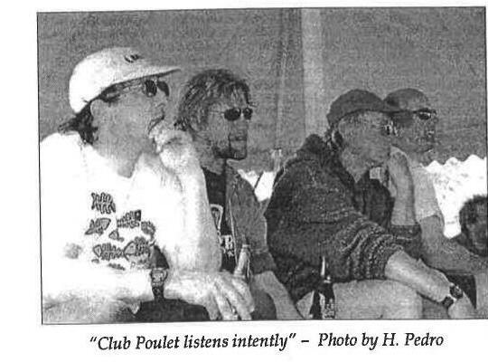 Four men sitting and listening intently, captioned 'Club Poulet listens intently'. Photo by H. Pedro