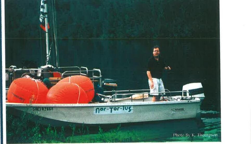 The boat Nor-Tor-Ius loaded with orange fenders, a crew member standing aboard at the dock