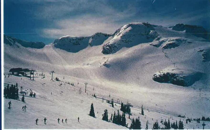 A ski hill at Whistler, BC, with a chairlift and skiers on the slope