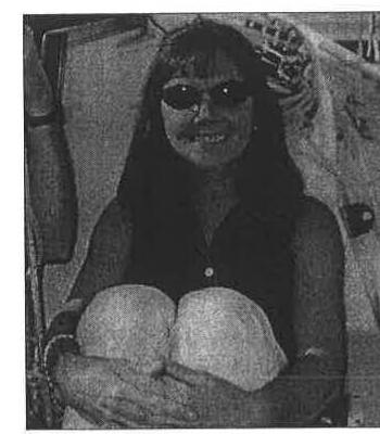 Commodore Heather Macnaughton smiling, holding a sail bag aboard a boat