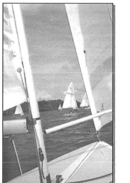 View forward between a mainsail and jib on an Albacore, with other dinghies racing in the background