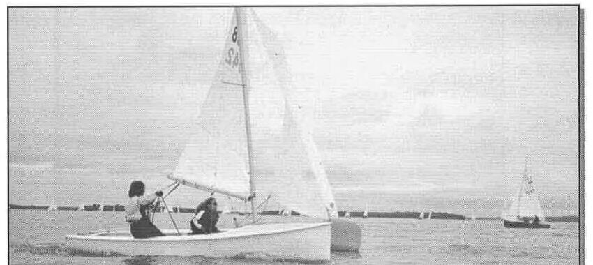 Two crew racing an Albacore close-hauled, with another boat visible in the distance