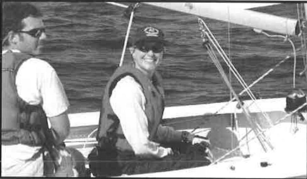 Helm and crew aboard an Albacore, the crew smiling at the camera while hiking out