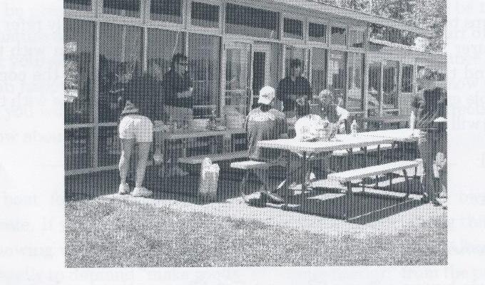 Members gathered at picnic tables outside a clubhouse