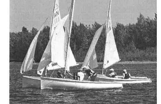 A fleet of Albacores racing near shore, several boats overlapped