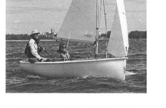 A sailor and crew in an Albacore off Hamilton, city skyline in the background